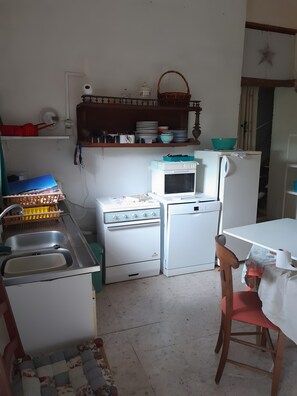 Eine kleine Küche mit Spüle, Herd, Mikrowelle und Kühlschrank.