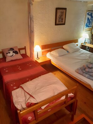 Ein Zimmer mit zwei Betten, einem Nachttisch mit Lampe, einem Holz-Kopfteil und einem Wandbild.