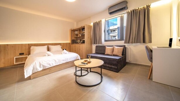 Een moderne hotelkamer met een bed, een bank, een ronde tafel en ingebouwde opbergruimte.