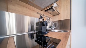 Een kleine keuken met een roestvrijstalen koelkast, een spoelbak en een houten aanrecht.