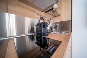 Eine kleine Küche mit einem Edelstahl-Kühlschrank, einer Spüle und einer Holzausziehtafel.