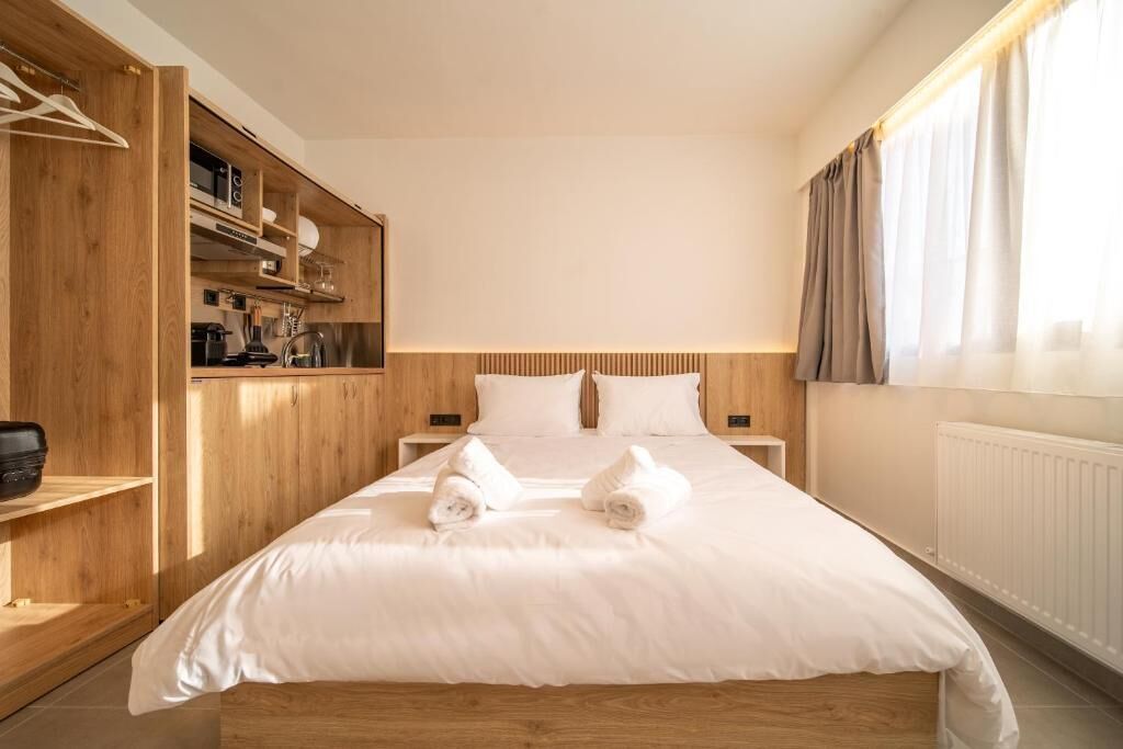 Ein Hotelzimmer mit einem hölzernen Bett, weißen Bettwäsche, einem Nachttisch und einem eingebauten Kleiderschrank.