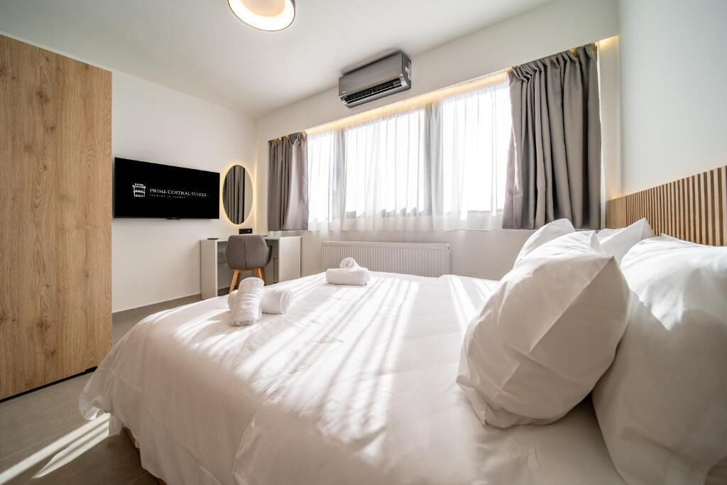 Ein Hotelzimmer mit Bett, Fernseher, Fenster mit Vorhängen und Klimaanlage.