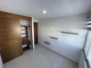 Ein Zimmer mit einem Holzkleiderschrank, einer Heizung und einem weiß gefliesten Boden.