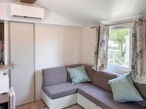 A room with a sofa, a window with curtains, an air conditioning unit, and a door. - Unit 1 – Tournesols
Spacious, Relaxing, Ready for Your Next Holiday (Lévignac-de-Guyenne)