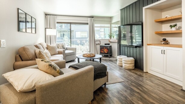 Una sala de estar con sofá, sillón, televisor y estufa de leña.