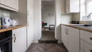 Una cocina estrecha con armarios blancos, una encimera de madera, un tostador y un lavabo.