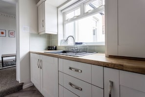 Eine Küche mit Fenster, weißen Schränken, einer Spüle und einer Arbeitsplatte.
