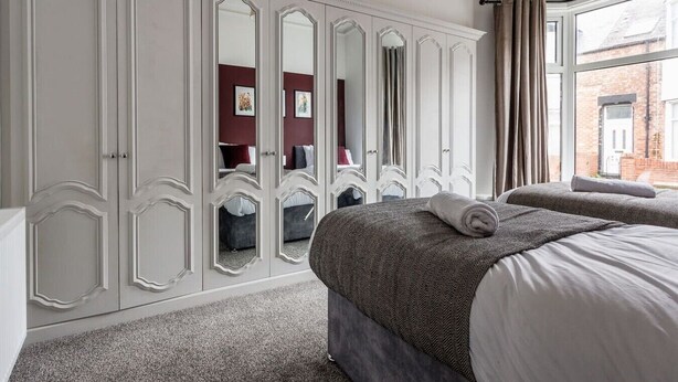 Un dormitorio con un armario grande, dos camas y vistas al exterior.