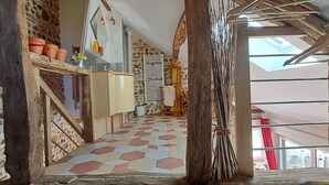 A rustic interior with stone walls, a tiled floor, a wooden staircase, and a view through a skylight. - “L'air De Vacances” Cottage with Private Terrace and Wi-Fi (Bonnée)