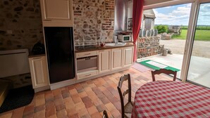 A kitchen with stone walls, a refrigerator, oven, and a window with a view of the countryside. - “L'air De Vacances” Cottage with Private Terrace and Wi-Fi (Bonnée)