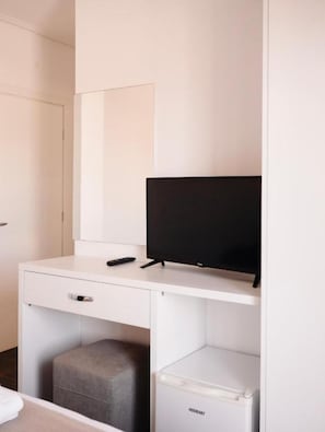 A hotel room with a white desk, a television, a small ottoman, and a white cabinet. - Hotel Keli Ksamil (Ksamil)