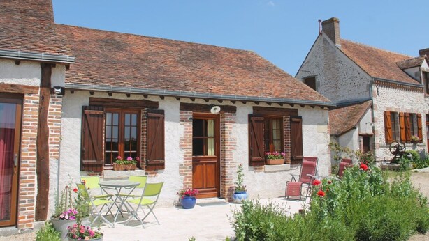 A traditional stone house with a tiled roof, wooden shutters, and a small patio with outdoor seating. - Bed and Breakfast 'L'églantier' (Bonnée)