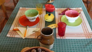 A dining table set with various dishes and utensils, surrounded by wooden chairs. - Bed and Breakfast 'Roulotte Esméralda' with Balcony, Wi-Fi and Air Conditioning (Bonnée)