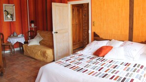A room with a bed, a chair, a table, and a door. - Bed and Breakfast 'Volière' with Wi-Fi (Bonnée)