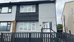 A two-story residential building with a black and white exterior, a gated entrance, and a visible door with a number plate. - Shepherd's Lodge (Skipton)