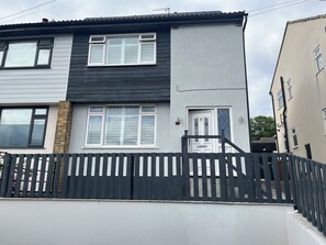A two-story residential building with a black and white exterior, a gated entrance, and a visible door with a number plate. - Shepherd's Lodge (Skipton)