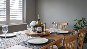 A dining table set with plates, cutlery, a wine bottle, glasses, and a decorative centerpiece. - Shepherd's Lodge (Skipton)