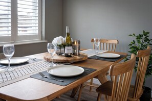 A dining table set with plates, cutlery, a wine bottle, glasses, and a decorative centerpiece. - Shepherd's Lodge (Skipton)