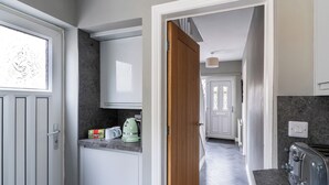 A kitchen with a wooden door, a coffee maker, and a toaster. - Shepherd's Lodge (Skipton)