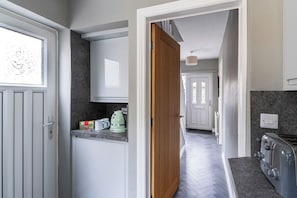 A kitchen with a wooden door, a coffee maker, and a toaster. - Shepherd's Lodge (Skipton)