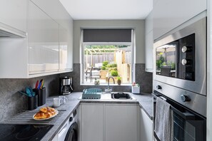 Cozinha compacta com forno embutido, cafeteira e vista para o quintal.