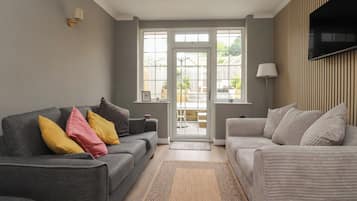A living room with two sofas, a patterned rug, and a television mounted on the wall.