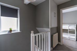 A room with a window, a radiator, a white railing, and a bunk bed. - Shepherd's Lodge (Skipton)
