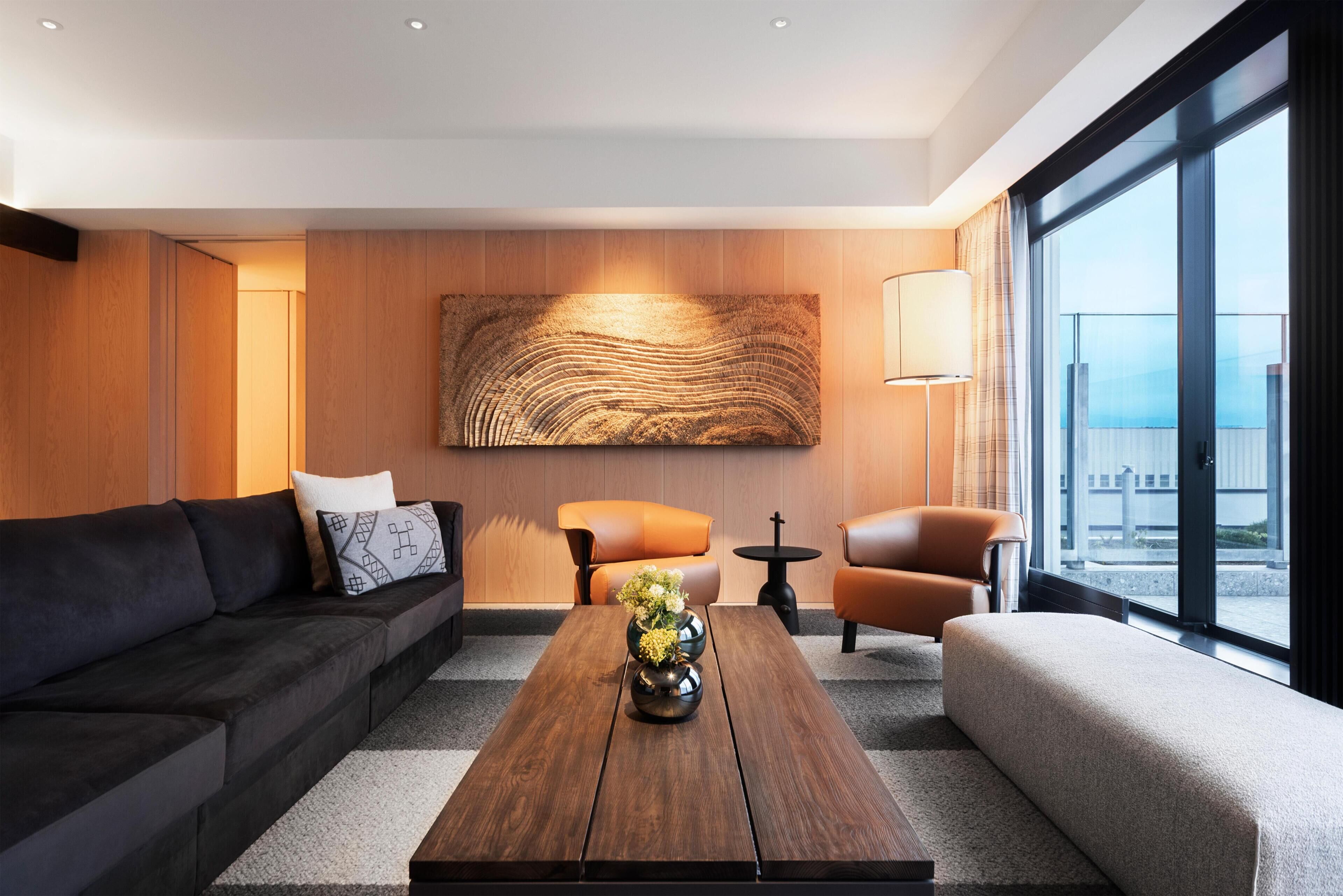 Una sala de estar moderna con un sofá, sillones, una mesa de centro y un cuadro abstracto grande en la pared.
