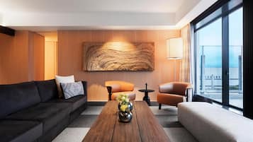 Una sala de estar moderna con un sofá, sillones, una mesa de centro y un cuadro abstracto grande en la pared.