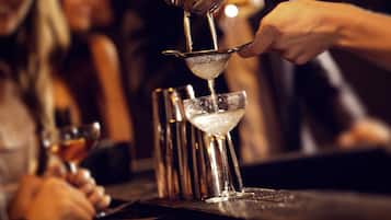 Un cantinero sirviendo una bebida en una copa de martini.