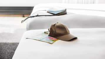 Une casquette posée sur un canapé blanc, avec un magazine et un sac en arrière-plan.