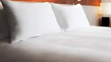 A neatly made bed with white linens and a wooden headboard.