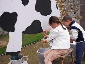 Une grande décoration représentant une vache, qu’une personne est en train de peindre.