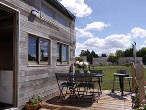 A wooden deck with a table and chairs, a basket with plants, and a fence in the background. - Tiny house at the educational farm | Spa included | 1h30 from Paris (Villiers-Saint-Orien)