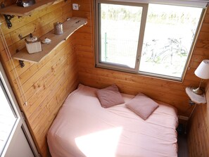 A small cabin with a single bed, a window, and a shelf with items. - Tiny house at the educational farm | Spa included | 1h30 from Paris (Villiers-Saint-Orien)