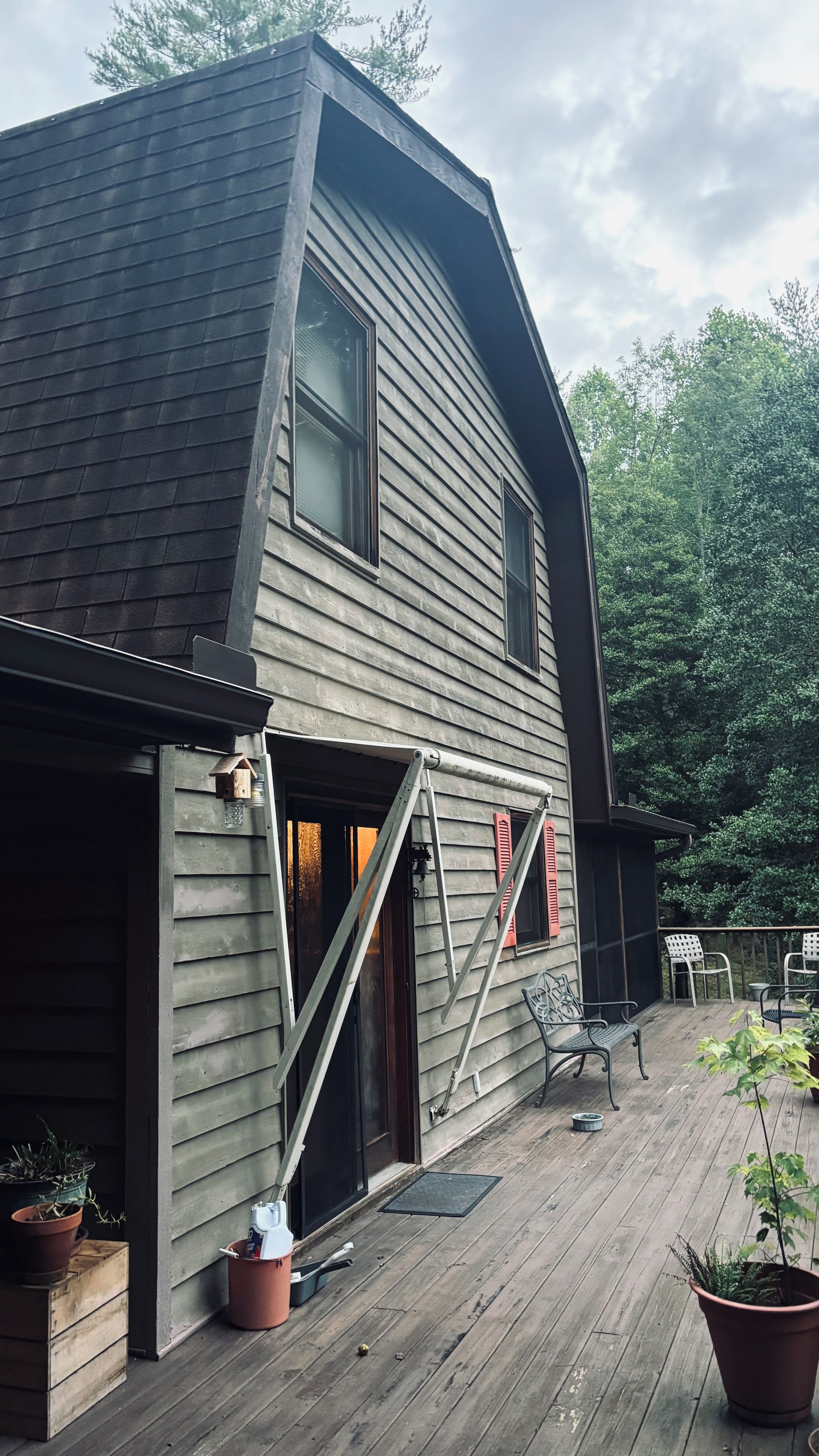 A house with a sloped roof, a garage door, and a wooden deck with potted plants.
