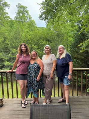 A wooden deck with a railing, surrounded by lush greenery. - 3-bedroom country house in charming Murphy with AC (Murphy)