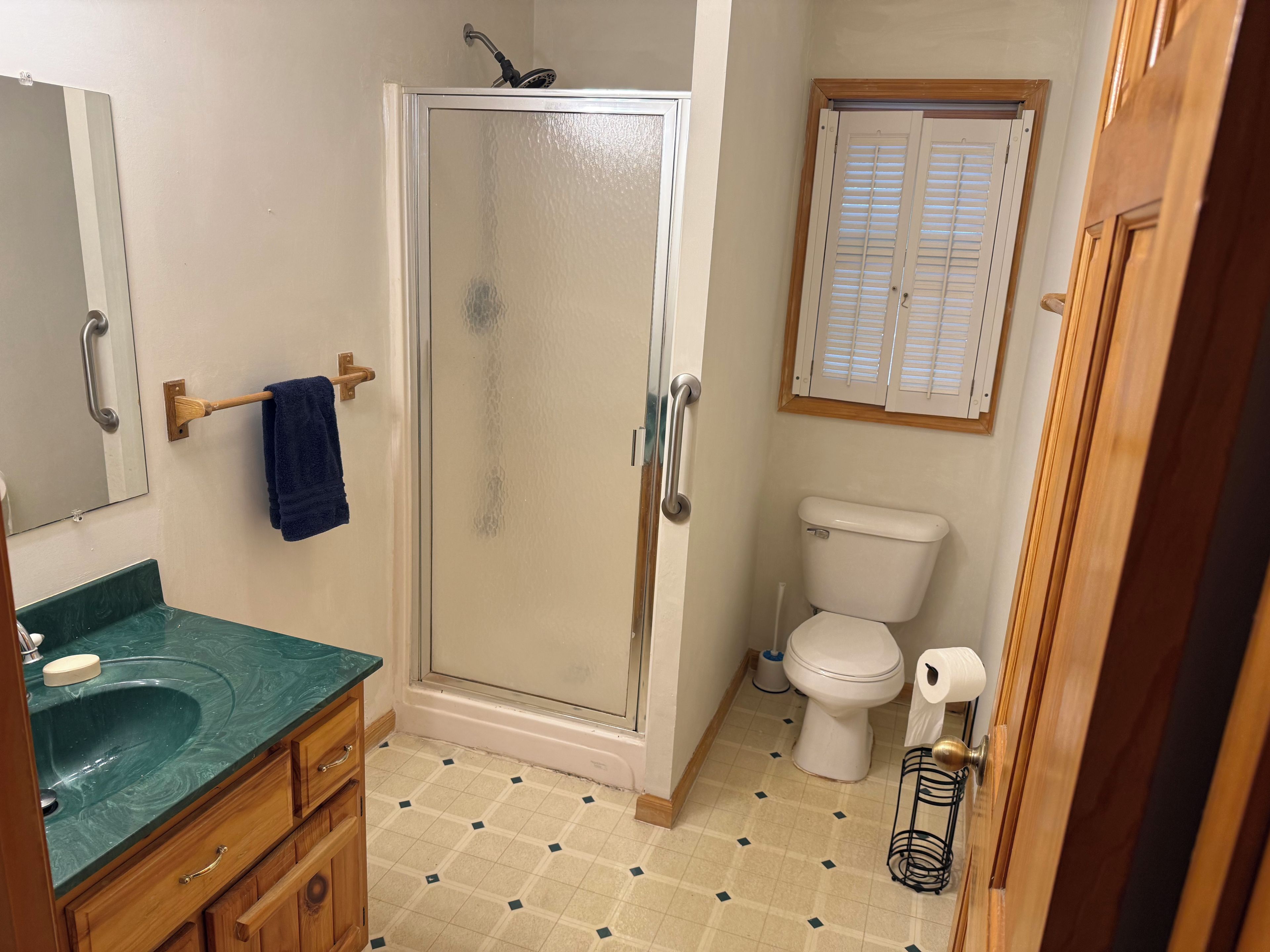 A bathroom with a shower, toilet, sink, and a mirror.