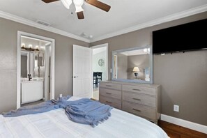 A bedroom with a bed, a dresser, a mirror, and a ceiling fan. - Villa Varges - Be our Guest! (Lehigh Acres)