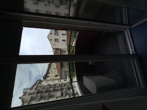 A view through a window with a building in the background, a balcony, and a door frame. - Bright Studio Apartment with Parking Space 205 (Milano)