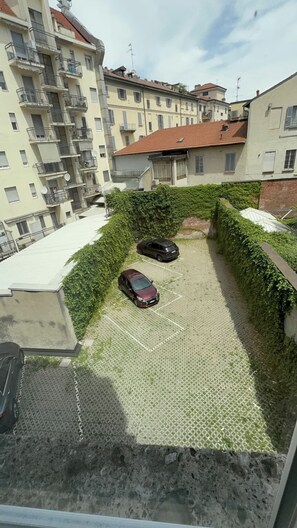 A residential area with a paved parking space and two cars parked. - Bright Studio Apartment with Parking 205 (Milano)