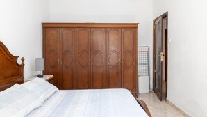 Een slaapkamer met een bed, een kledingkast, een nachtkastje en een deur.
