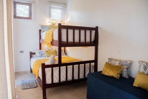A bunk bed with a lower bunk, a bedside table, and a nightstand. - A Touch of Paradise: Villa Bahia Rincon (Samaná)