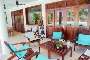 A room with wooden furniture, including chairs and a table, and large glass doors leading to an outdoor area. - A Touch of Paradise: Villa Bahia Rincon (Samaná)