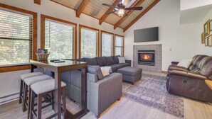 Un salón moderno con techo alto, chimenea y ventana grande.