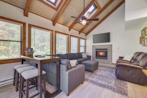 Ein modernes Wohnzimmer mit hoher Decke, Kamin und großem Fenster.