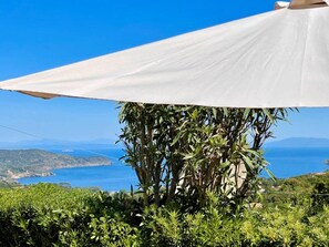 Eine weiße Sonnenschirmkonstruktion mit Blick auf das Meer und die Hügel im Hintergrund.