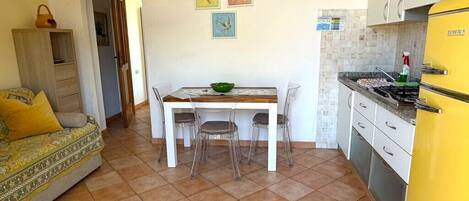 A compact living space with a dining area, kitchenette, and a sofa.
