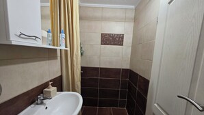Un baño con lavamanos, ducha e inodoro.